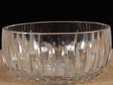 a clear glass bowl on a table with a black background