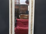a mirror that is sitting on the floor in front of a red couch