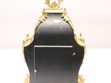 a black and gold clock sitting on a white surface