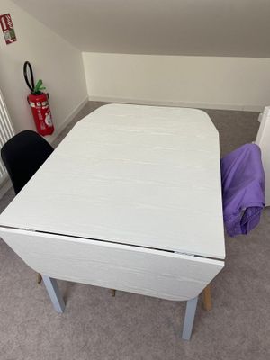 une table blanche sur laquelle est posé un sac violet