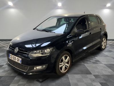 La Volkswagen Polo noire est garée dans une pièce au sol carrelé en damier.