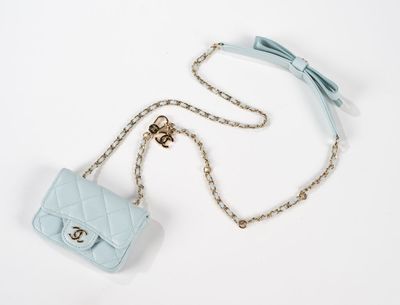 un gros plan sur un petit sac à main bleu orné d'un nœud et suspendu à une chaîne