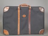 a black suitcase with a brown handle on a gray surface