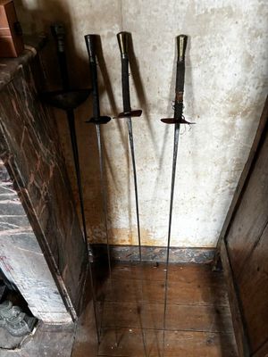 three swords that are standing on a wooden floor