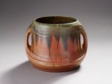 un vase marron et vert muni d'anses, sur un fond blanc