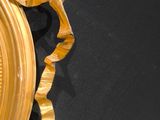 a gold oval mirror hanging on a black wall