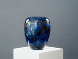 un vase bleu posé sur un socle blanc