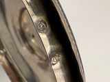 a close up of a silver clock on a table