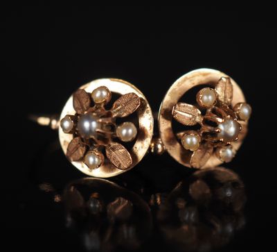 une paire de boucles d'oreilles en or ornées de perles sur un fond noir