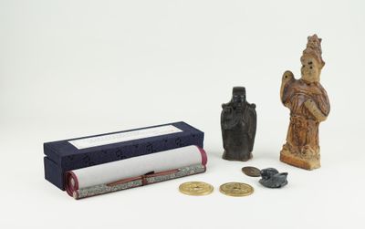 a small statue next to a small book and some coins
