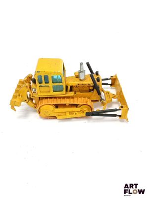 un bulldozer miniature posé sur une surface blanche