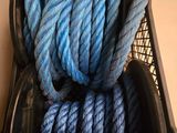 un panier noir rempli de corde bleue, à côté d'un tas de cordes rouges et blanches