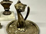 a statue of a cat sitting on a plate next to a candle holder