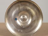 a metal object on a wooden table with a blue dot on it