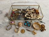 une boîte en verre remplie de bijoux divers, posée sur une table