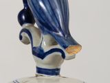 a blue and white vase with a bird on top of it