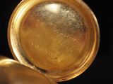 a close up of a gold pocket watch with a black background