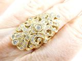 a woman ' s hand holding a gold ring with diamonds on it