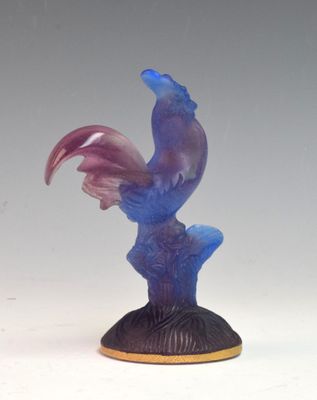 une statue d'oiseau violette et bleue posée sur un socle noir