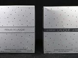 a close up of two boxes of perfume on a black surface