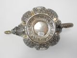 an antique silver teapot with ornate decoration on a white background
