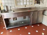 a large stainless steel counter in a kitchen with tile flooring
