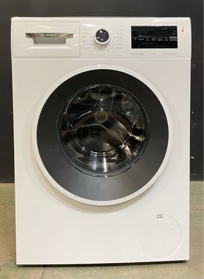 une machine à laver posée à même le sol, près d'un mur