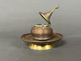 an antique brass cup and saucer on a saucer on a gray surface