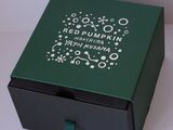 a green box with a black lid and a white writing on it