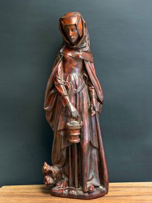 a wooden statue of a woman holding a bucket and a dog