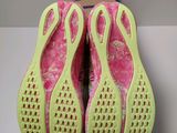 pink and green slippers on a white surface with a book in the background