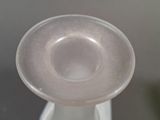 a clear glass vase with a white base on a table