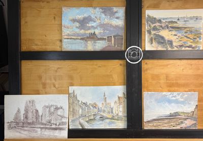 quatre tableaux posés sur une étagère, devant laquelle se trouve une horloge