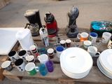many cups and plates on a table with a coffee maker