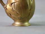 a gold vase with a bird on it sitting on a table