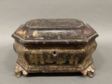an old black and gold box sitting on top of a table