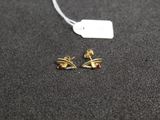 a pair of gold earrings on a black surface with a price tag