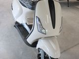 un scooter blanc garé dans un garage, avec d'autres scooters en arrière-plan