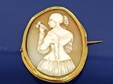 une image représentant une femme tenant un oiseau dans la main, sertie dans une broche en or