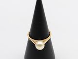une bague en or ornée d'une perle posée au sommet d'un cône noir