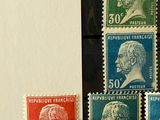 four different colored postage stamps on display in front of a window
