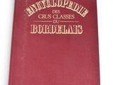 an old red book with gold lettering on it sitting on a white surface