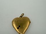 a close up of a gold heart pendant on a white surface