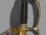 a close up of a gold and black sword on a gray background