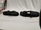 two pairs of black sandals sitting on a white surface