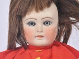 a close up of a doll with a red dress on