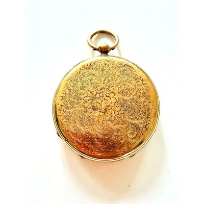 une montre de poche dorée posée sur une surface blanche