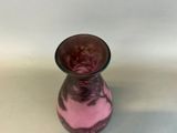 a pink vase sitting on a table with a white wall in the background