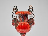 un vase orange posé sur une table près d'un mur blanc