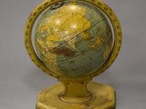 yellow and green globe on stand on grey background with grey background